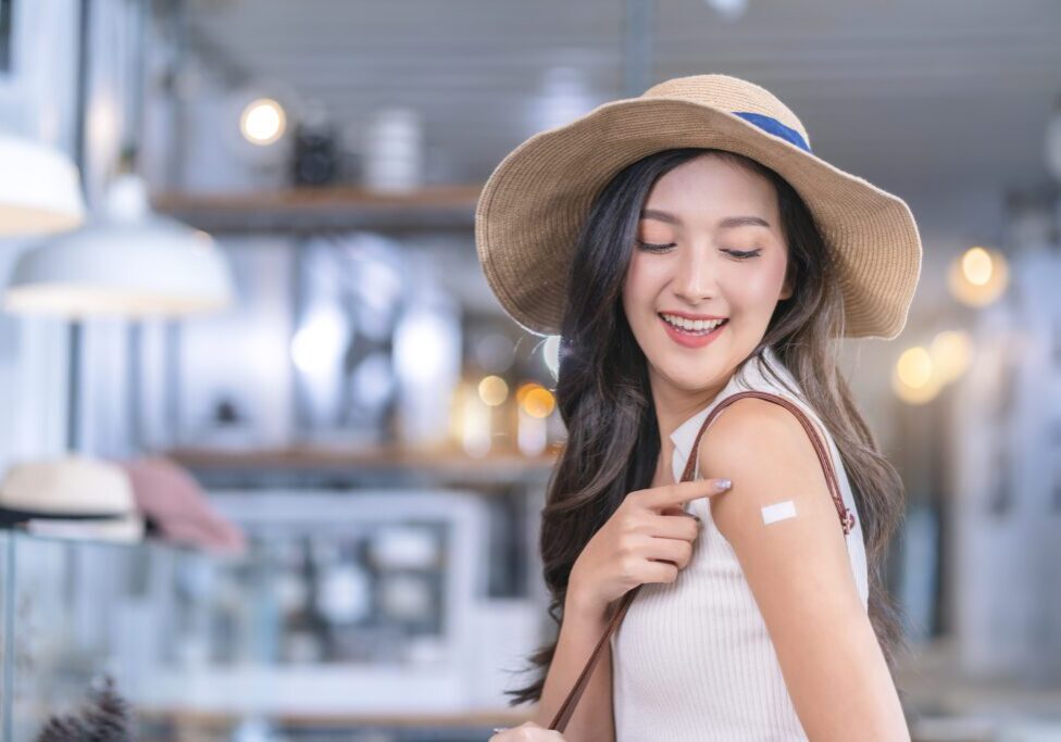 Asian female cheerful smiling teenager hand gesture point show vaccine brand against covid-19 with  happiness healthy after getting vaccine prevent
